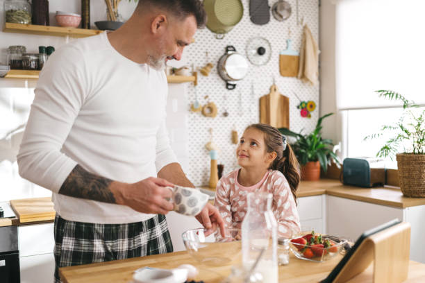 istock Happy father and daughter making breakfast in the kitchen. 1450657154