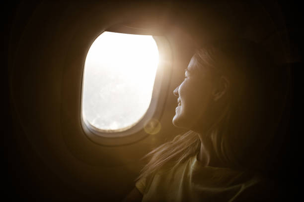 istock Happy woman enjoying while looking through airplane window. 1450657544