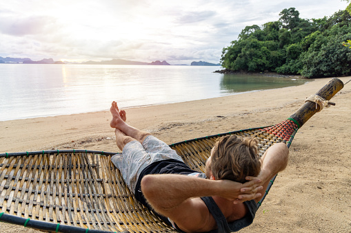 30's man relaxing on hammock over sea in Thailand, Southeast Asia vacations.