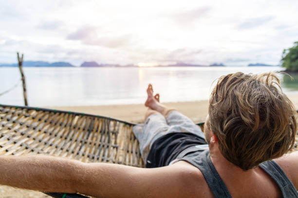 30's man relaxing on hammock over sea in Thailand, Southeast Asia vacations.