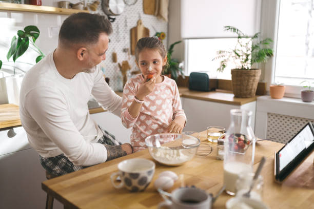 istock Happy father and daughter making breakfast in the kitchen. 1450658911
