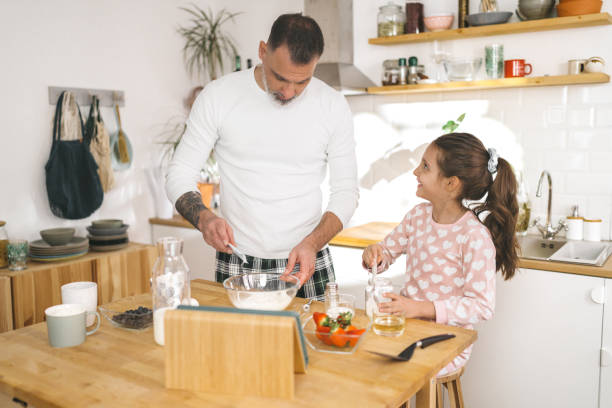 istock Happy father and daughter making breakfast in the kitchen. 1450659496