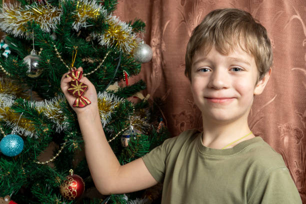 A child dresses up a Christmas tree with toys according to family tradition. Decoration of the apartment for the holiday of Christmas and New Year. Christmas Eve with family. High quality photo