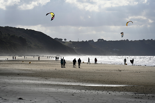 Erquy, France, September 24, 2022 - Tourists and locals on Caroual beach flying kites, kiteboarding and kitesurfing, Brittany.