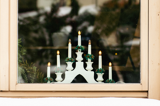 Traditional Swedish Christmas candlestick bridge by a wooden window with snow on the windowsill