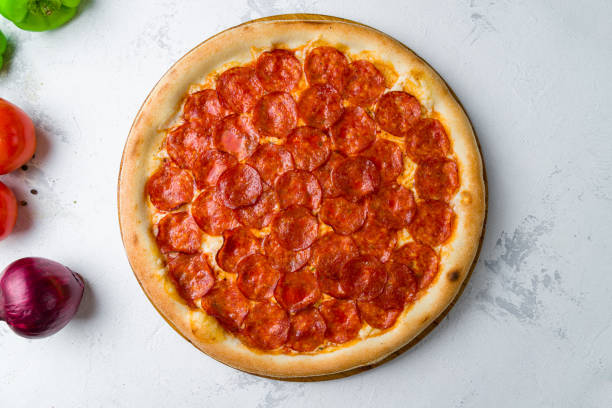 istock Pepperoni pizza on wooden board on concrete table top view 1450671063