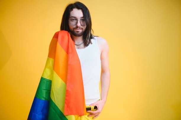 homem gay segurar bandeira listrada arco-íris isolado no retrato de estúdio de fundo colorido. pessoas estilo de vida moda lgbtq conceito - twink - fotografias e filmes do acervo