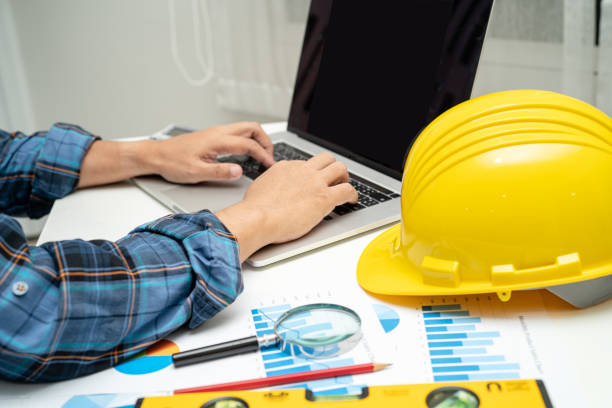 istock Asian engineer and partner team learn and talk with house plan project blueprint, graph and yellow helmet and engineering construction tools on table work. 1450672597