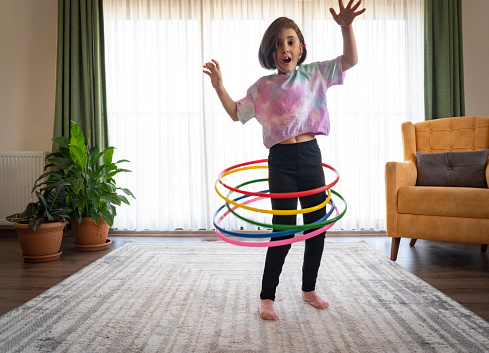 cute little girl playing with hula hoop in living room at home.