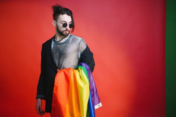 uomo gay tenere bandiera a strisce arcobaleno isolato sul ritratto di studio sfondo colorato. persone lifestyle moda concetto lgbtq - twink foto e immagini stock