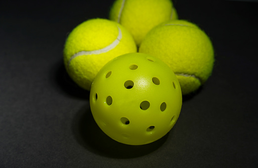 Pickle balls and Tennis balls on black background