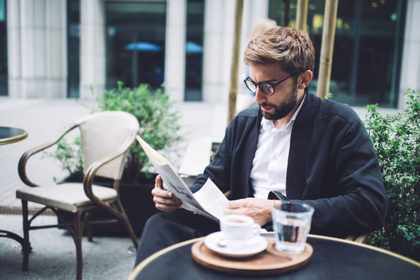 istock Serious businessman reading newspaper while having coffee in cafe 1450675174