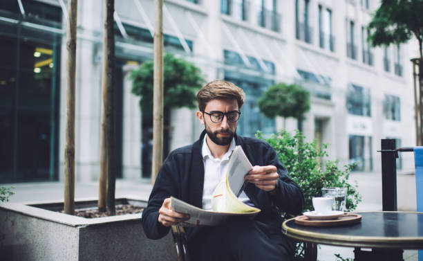 istock Man paging newspaper in street cafe 1450675199