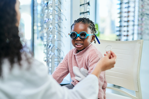 Test, optometry and child with optometrist for glasses, consultation and vision help at a clinic. Healthcare, check and optician helping an African girl patient with an exam on her eyes with a lens