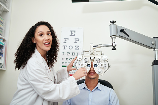 Optometrist, woman and client for eye test, in office and communication for appointment. Black medical professional, patient and eyecare with equipment, health or wellness for clear vision or checkup