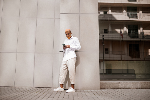Urban style. A picture of a tall dark-skinned man in white clothes on a urban background