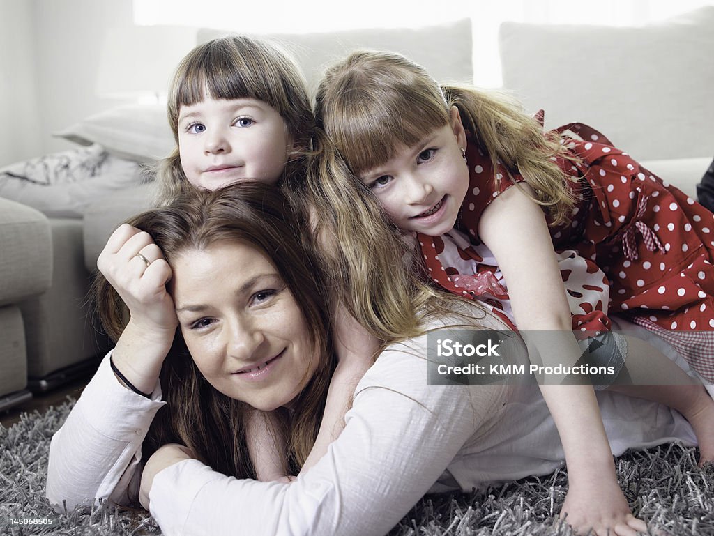 Mother and daughters laying on rug  2-3 Years Stock Photo