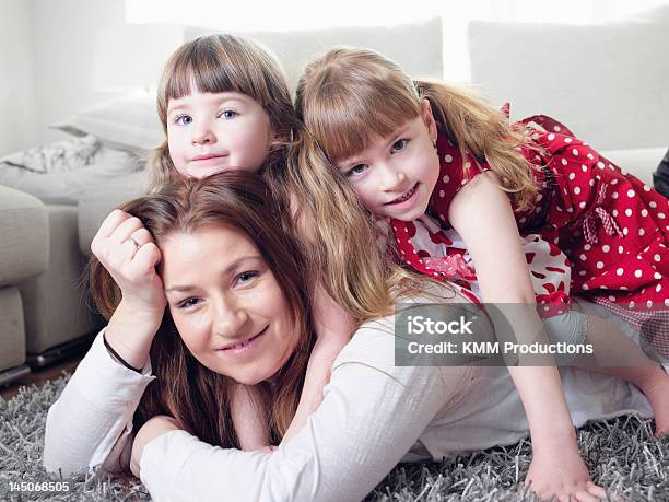 Mother And Daughters Laying On Rug Stock Photo - Download Image Now - 2-3 Years, 30-39 Years, 35-39 Years