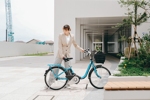 A busy businesswoman parks a shared bicycle at work for a sustainable lifestyle.
