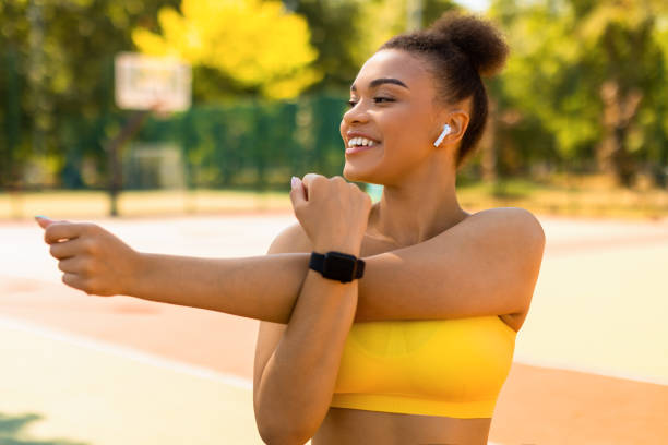 mujer negra deportiva con ropa deportiva amarilla estirando los brazos - deltoid fotografías e imágenes de stock