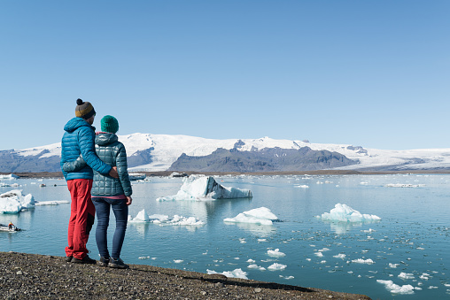 Young heterosexual couple looking at Jökulsárlón glacier lagoon in Iceland.