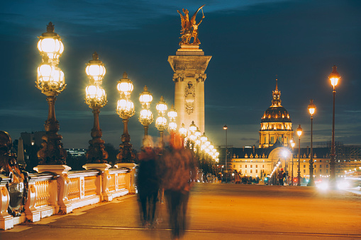 Pont Alexandre III with Les Invalides by night in Paris, France
