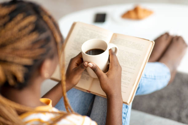 istock Unrecognizable african american woman reading book, drinking coffee 1450704185