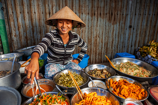 Vietnamese woman selling home made food at her food stand on the local market, Central Vietnam.