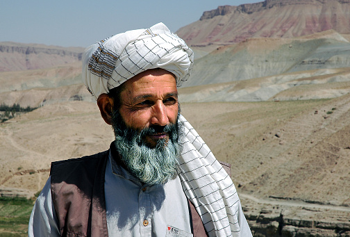 Village between Herat and Qala-e-Naw, Herat Province / Afghanistan: A local Afghan man wearing a turban with a backdrop of mountain scenery in a remote part of western Afghanistan.