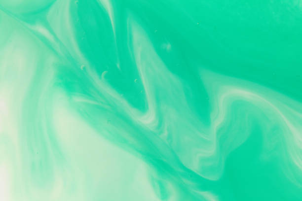 Macro close up depicting the abstract forms and shapes in a mixture of green paint and oil.