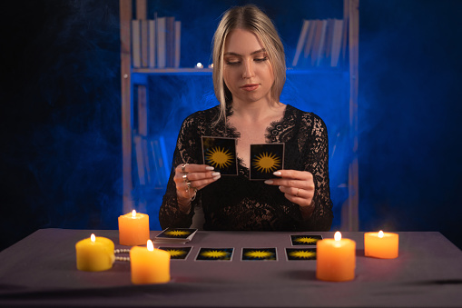 Female fortune teller read tarot cards to predict fortune. Future reading. Ritual candles burning, seance, smoke.