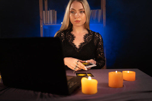 Psychic Tarot Card Reader on Laptop Computer. Focused video blogger telling her audience about oracle cards