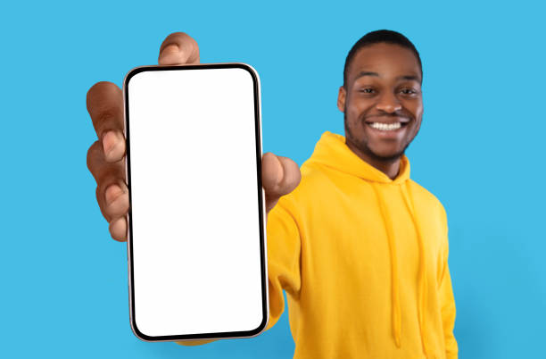 istock Mobile Ad. Joyful Black Guy Showing Big Blank Smartphone With White Screen 1450714441