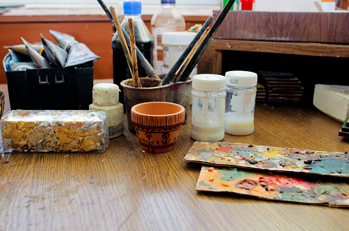 Workflow of the artist in the studio. Brushes and paints on art workplace.