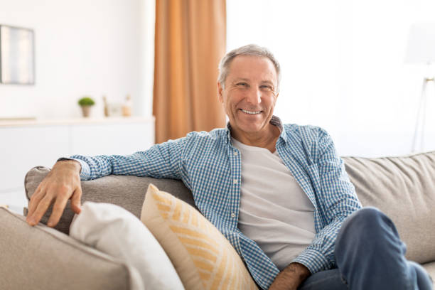 istock Smiling mature man sitting on the couch and posing 1450719937