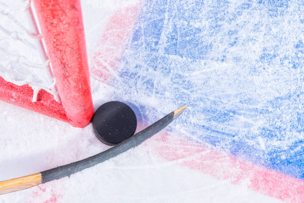 Almost scoring a goal in ice hockey Attempting to score a goal in ice hockey, with the puck stuck between the goal post and the goal with a hockey stick. ice hockey net stock pictures, royalty-free photos & images