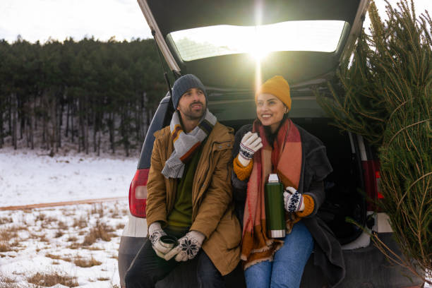 istock Couple sitting in a car trunk, drinking tea while resting after Christmas tree search 1450726920