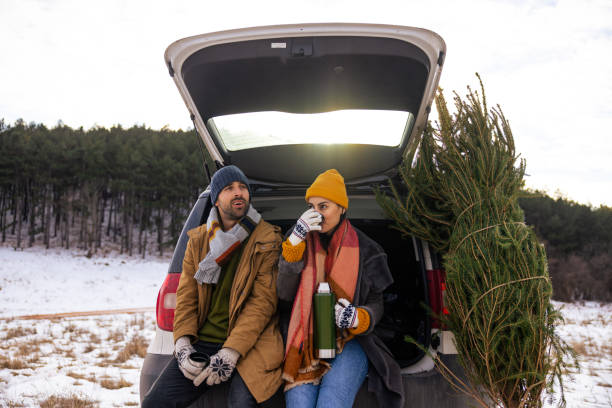 istock Couple sitting in a car trunk, drinking tea while resting after Christmas tree search 1450726934