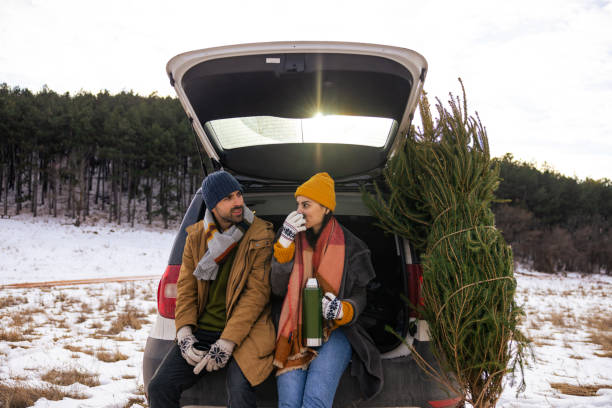 istock Couple sitting in a car trunk, drinking tea while resting after Christmas tree search 1450727115