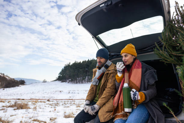 istock Caucasian couple sitting in a car trunk, drinking tea while resting after Christmas tree search 1450727253