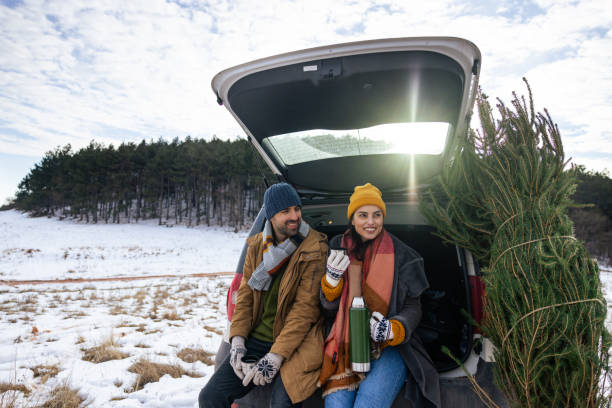 istock Caucasian couple sitting in a car trunk, drinking tea while resting after Christmas tree search 1450727418