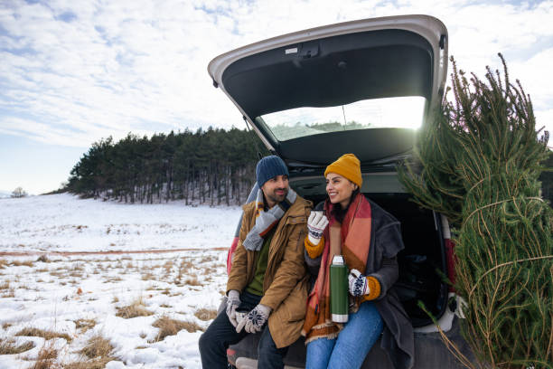 istock Caucasian couple sitting in a car trunk, drinking tea while resting after Christmas tree search 1450727420