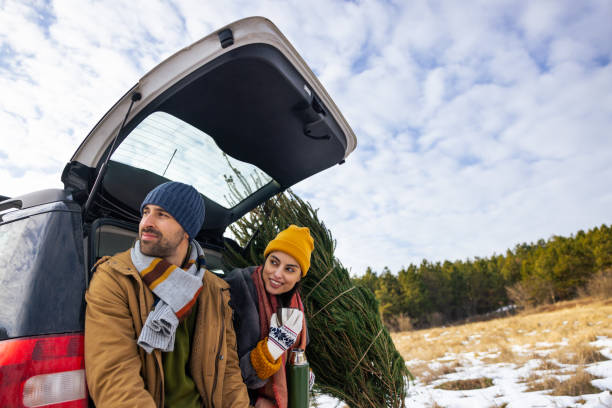 istock While resting after Christmas tree search, couple sitting on a car trunk, drinking tea and admiring view of nature 1450727544