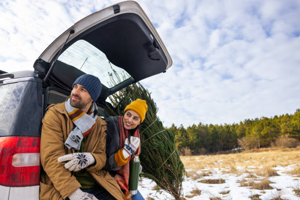 istock While resting after Christmas tree search, couple sitting on a car trunk, drinking tea and admiring view of nature 1450727654