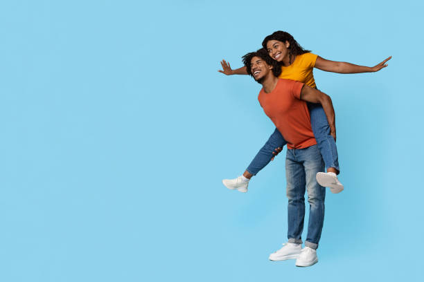 istock Funny african american guy holding girlfriend on his back 1450728317