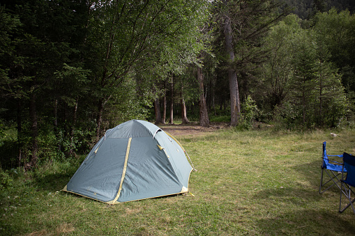 Camping in a tourist forest. A green tent set up on a picnic spot. High quality photo.