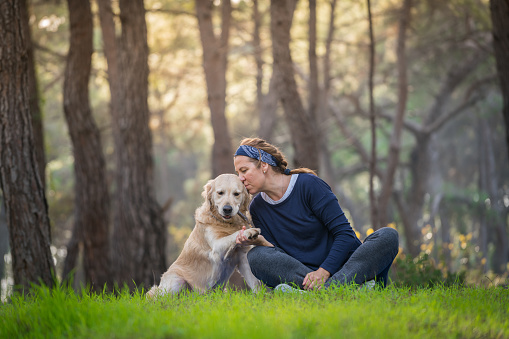 Lovely woman spend time and kissing her dog in forest.