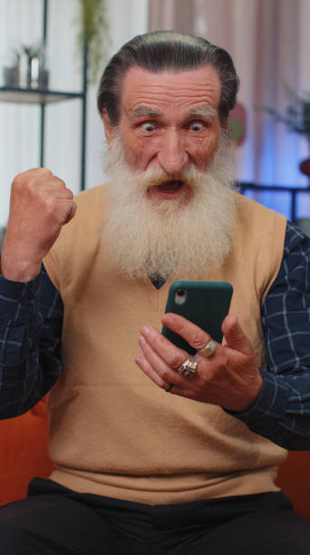 istock Senior grandfather at home use smartphone typing browsing, wow yes found out great big win celebrate 1450744721