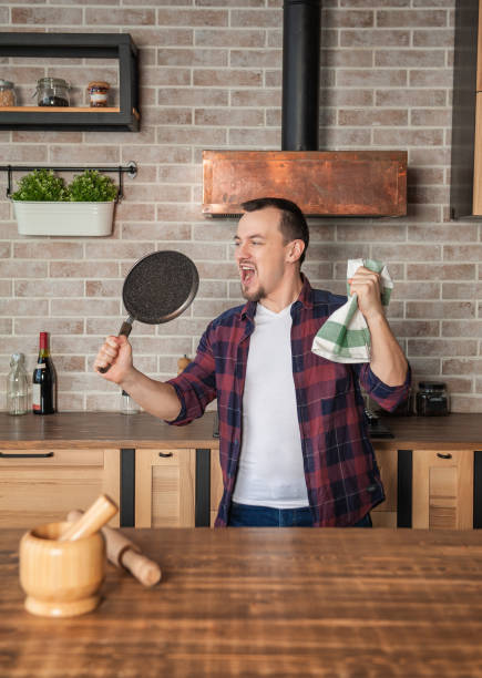 istock Smiling happy man singing with frying pan on the kitchen 1450747832