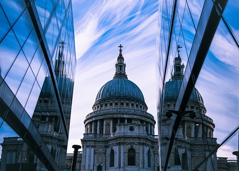 A low angle shot of St. Paul's Cathedral reflecting between modern buildings in London, England